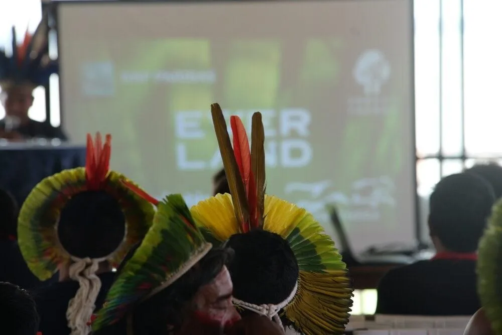 Indigenous community members in traditional feathered headdresses at an Everland forest conservation gathering